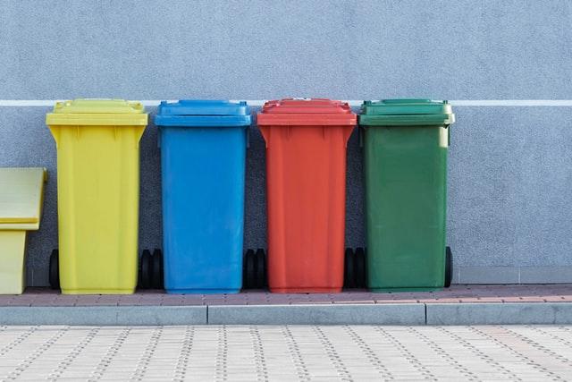 A picture of 4 bins of different colors used for recycling.