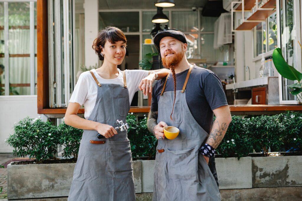 Two workers of a local cafe posing in front of a cafe.