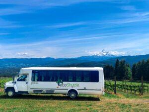 A charter bus parked in wine country looking at mount hood.