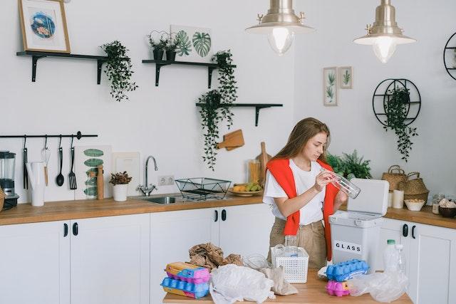 Woman in a kitchen sorting out trash to start a successful home recycling program
