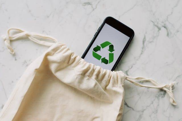An eco-friendly bag and a recycle logo on a mobile phone 