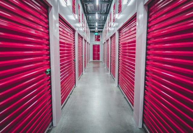 Alt-tag: A hallway in a storage facility with pink doors on both sides.