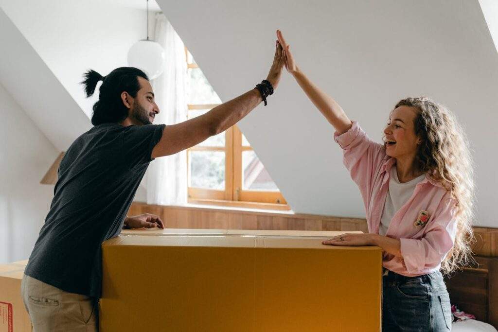 A couple high-fiving in front of a cardboard box