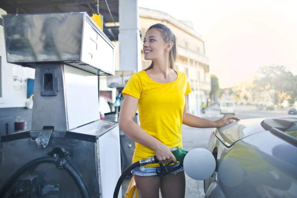 Alt. text: A girl in a yellow t-shirt filling her car with gas