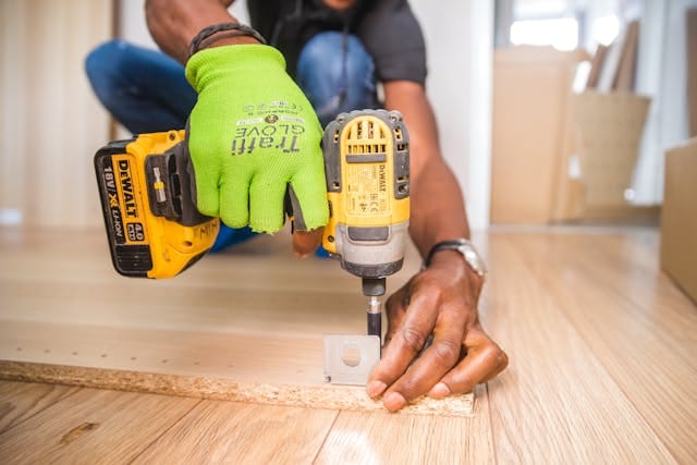 Person using a drill to repair furniture as part of a DIY home project.