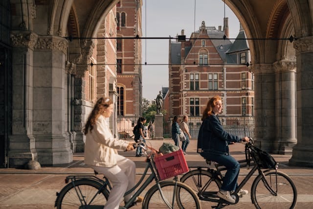 Two cyclists checking their bikes at a city intersection with bike helmets and urban traffic