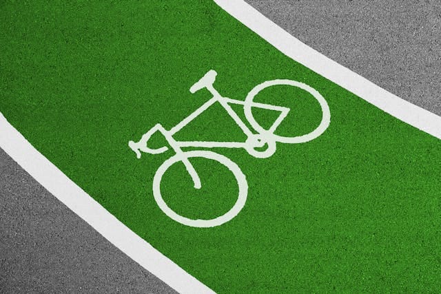  Bright green painted bike lane on city pavement with a white bicycle symbol